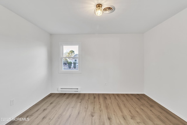 unfurnished room featuring a baseboard radiator and light hardwood / wood-style flooring