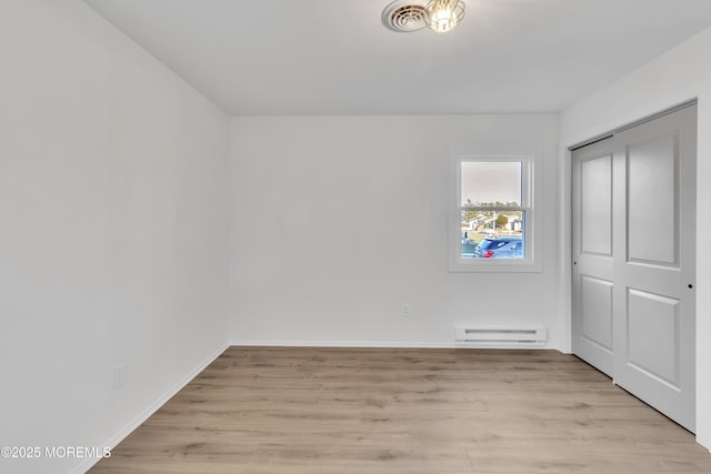 unfurnished bedroom featuring a baseboard radiator, light wood-type flooring, and a closet