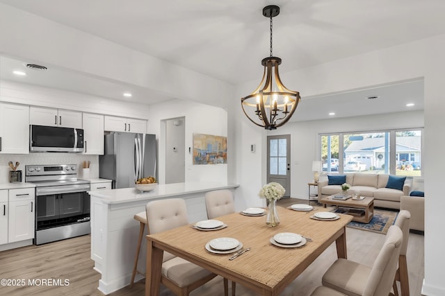 dining space with a chandelier and light wood-type flooring