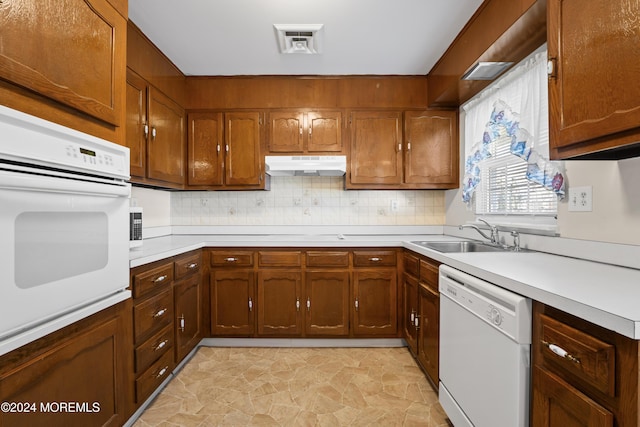 kitchen featuring white appliances, sink, and tasteful backsplash