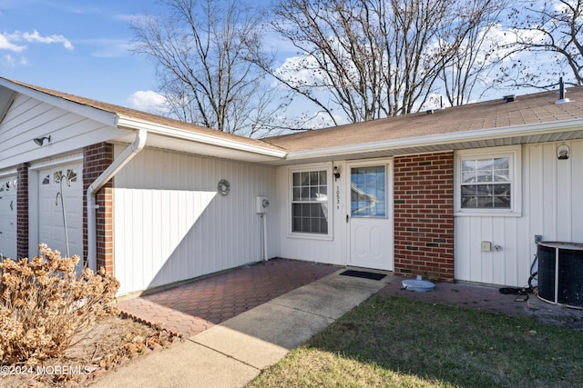 entrance to property with central AC unit and a garage