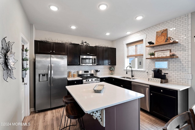 kitchen with a breakfast bar, a center island, sink, light hardwood / wood-style floors, and stainless steel appliances