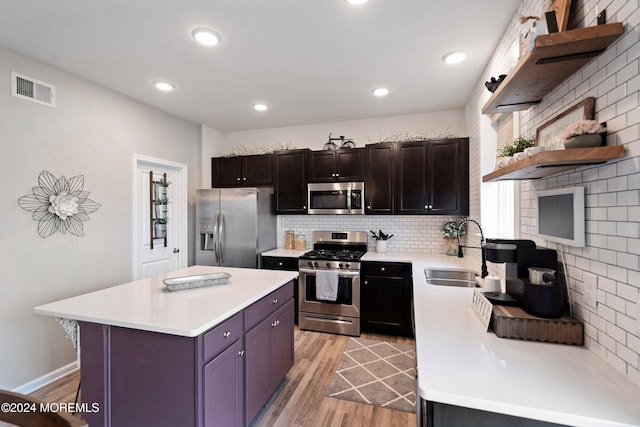 kitchen featuring light wood-type flooring, a breakfast bar, stainless steel appliances, sink, and a center island