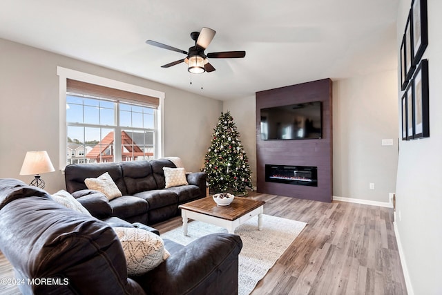 living room with a fireplace, light hardwood / wood-style floors, and ceiling fan