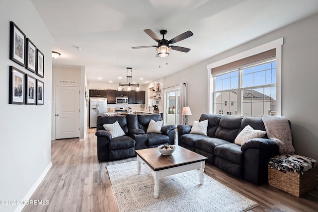 living room with ceiling fan, sink, and light wood-type flooring