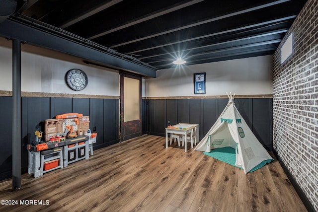 playroom featuring hardwood / wood-style floors and brick wall