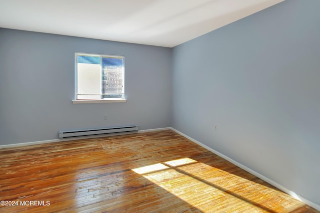 unfurnished room with wood-type flooring and a baseboard radiator