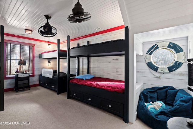 bedroom featuring light colored carpet and wooden walls