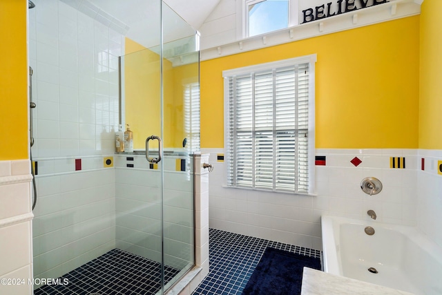 bathroom featuring plus walk in shower, vaulted ceiling, tile patterned floors, and tile walls