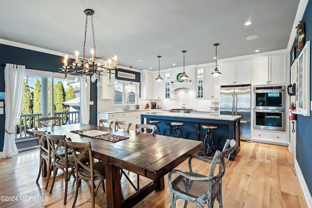 dining space with crown molding, a notable chandelier, and light wood-type flooring