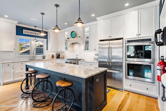 kitchen with a center island, white cabinets, crown molding, light wood-type flooring, and stainless steel appliances