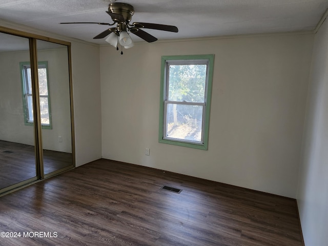 empty room featuring a textured ceiling, dark hardwood / wood-style floors, ceiling fan, and ornamental molding