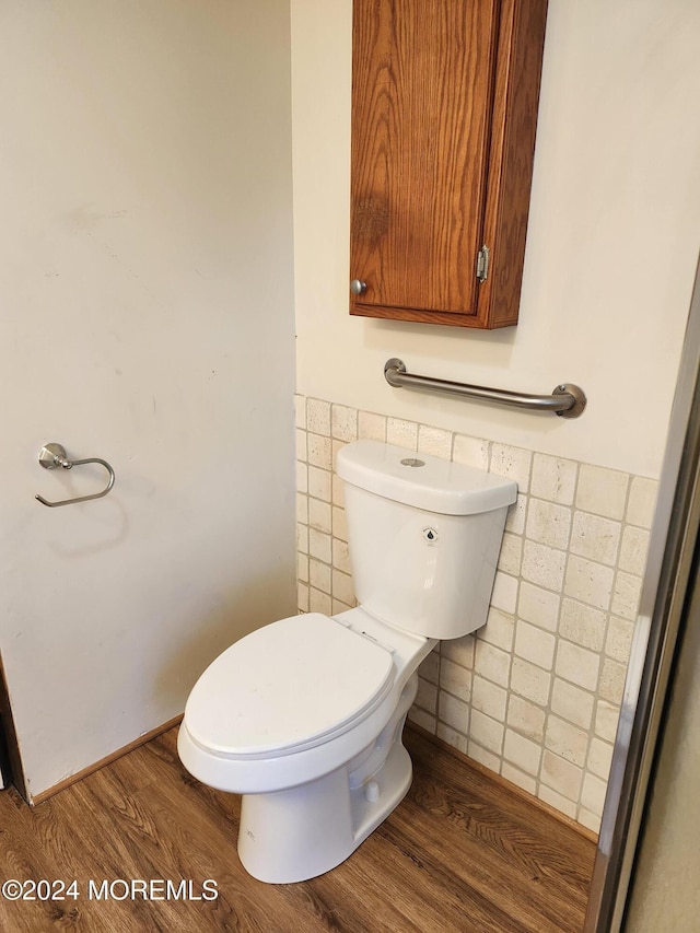 bathroom with hardwood / wood-style floors, toilet, and tile walls