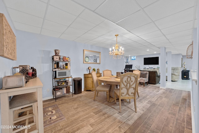 dining room featuring hardwood / wood-style floors, a drop ceiling, and a notable chandelier