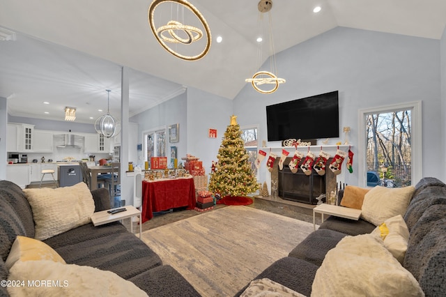 living room featuring high vaulted ceiling, ornamental molding, and a notable chandelier