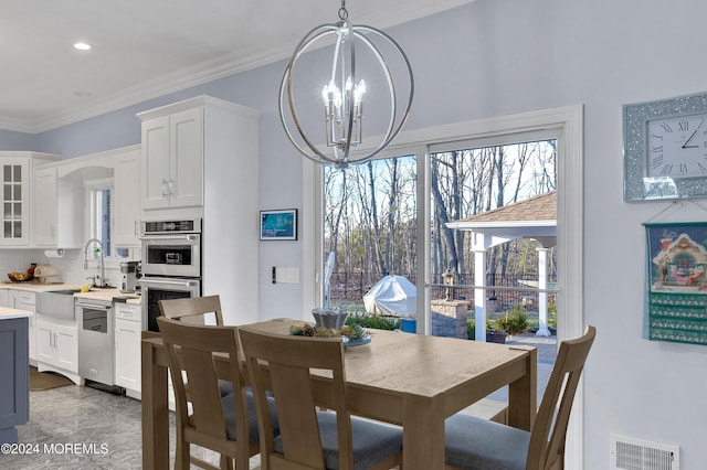 dining area featuring ornamental molding, a notable chandelier, and sink