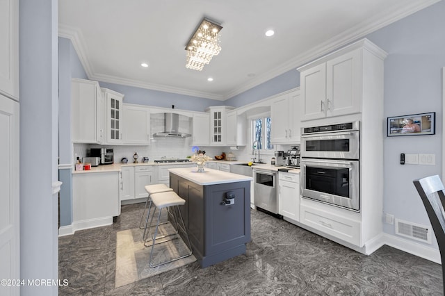 kitchen featuring a breakfast bar, a center island, white cabinets, wall chimney range hood, and stainless steel appliances