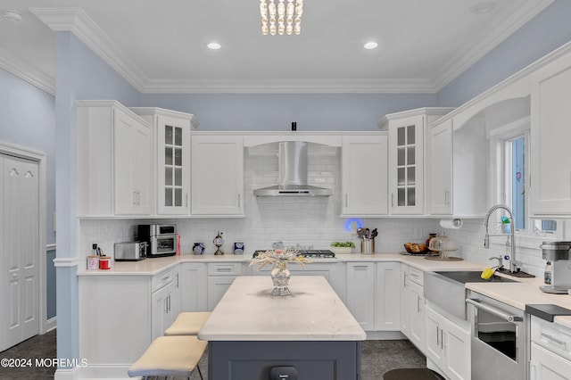 kitchen with white cabinets, sink, wall chimney exhaust hood, decorative backsplash, and ornamental molding