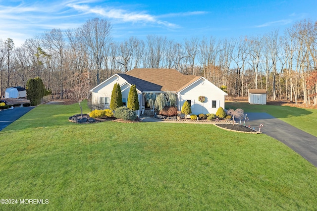 ranch-style home featuring a front lawn and a storage shed