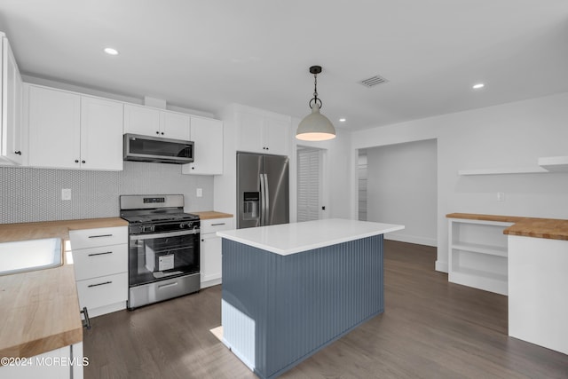 kitchen featuring wood counters, appliances with stainless steel finishes, a center island, white cabinetry, and hanging light fixtures