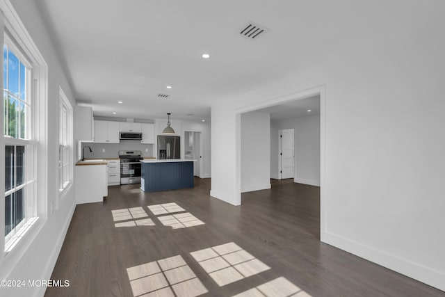 kitchen with a center island, white cabinets, sink, appliances with stainless steel finishes, and decorative light fixtures