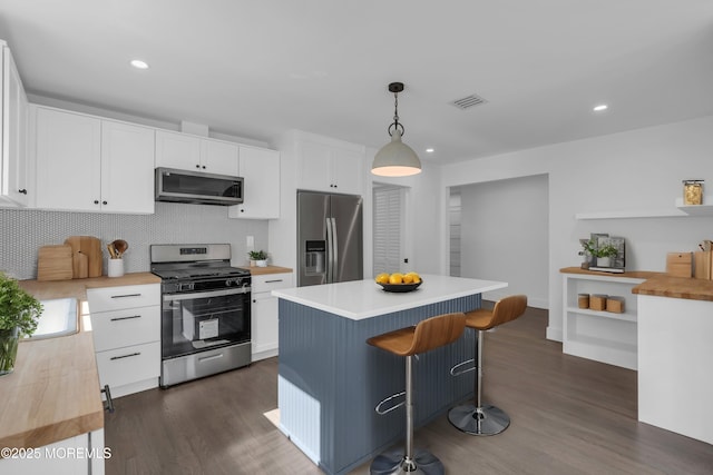 kitchen featuring a center island, white cabinets, hanging light fixtures, and appliances with stainless steel finishes