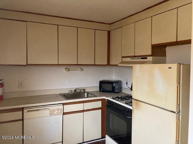 kitchen with cream cabinetry, white appliances, and sink