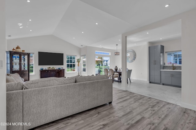 living room featuring light hardwood / wood-style floors, lofted ceiling, and sink