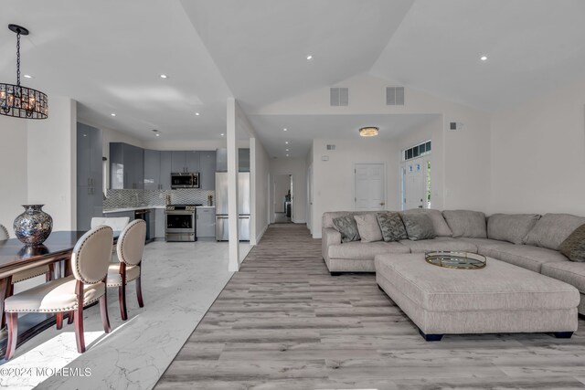 living room featuring a chandelier and lofted ceiling