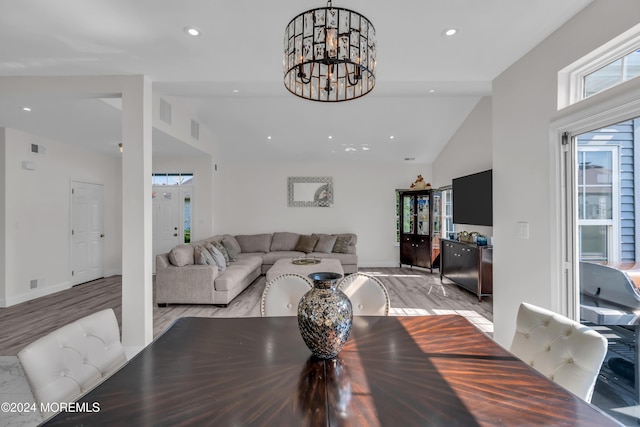 dining area with beam ceiling, light hardwood / wood-style flooring, high vaulted ceiling, and a notable chandelier