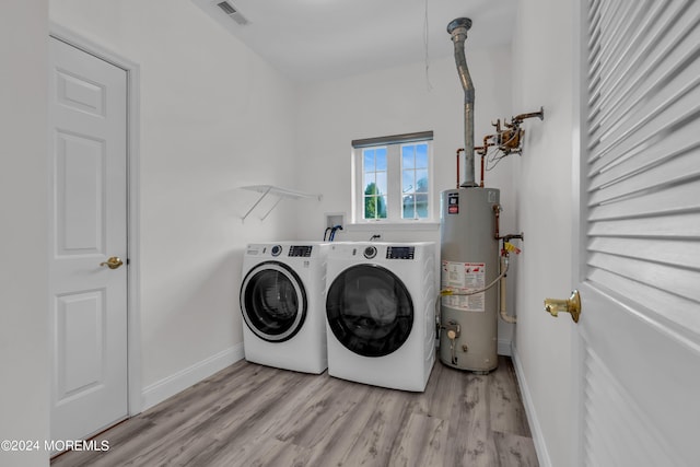 clothes washing area with separate washer and dryer, light hardwood / wood-style flooring, and gas water heater