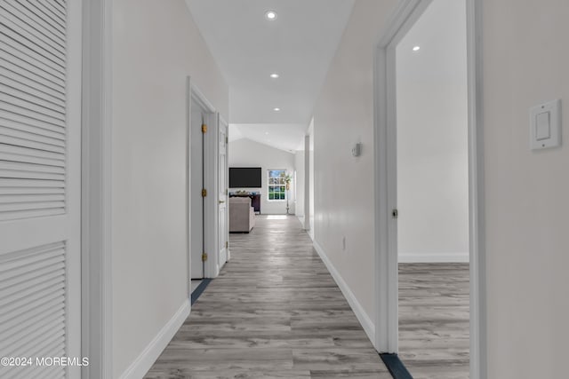 corridor featuring light hardwood / wood-style floors and vaulted ceiling