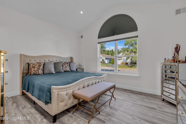 bedroom with light hardwood / wood-style floors and high vaulted ceiling