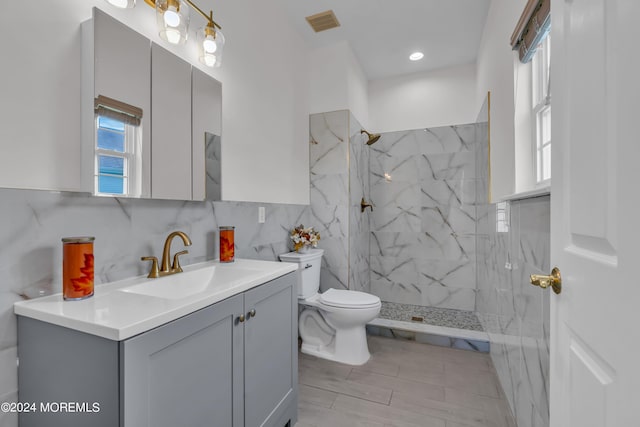 bathroom featuring a tile shower, decorative backsplash, vanity, and toilet