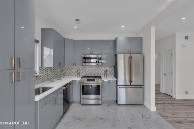 kitchen with backsplash, gray cabinetry, sink, and stainless steel appliances