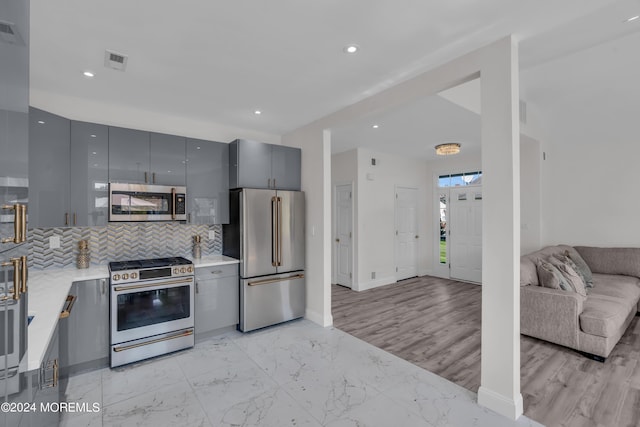 kitchen featuring backsplash, gray cabinets, and stainless steel appliances