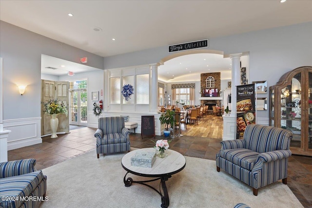 living room featuring plenty of natural light, ornate columns, a fireplace, and french doors