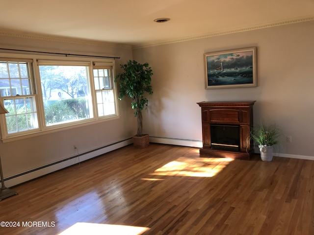 unfurnished living room featuring wood-type flooring, ornamental molding, and a baseboard heating unit