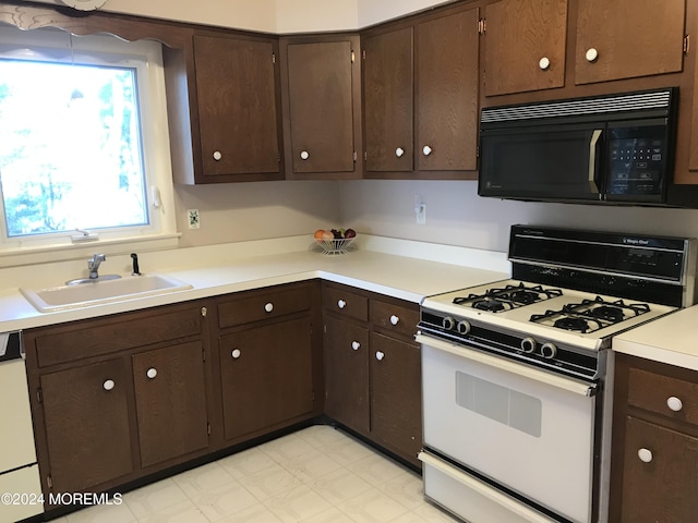 kitchen with dark brown cabinets, white appliances, and sink