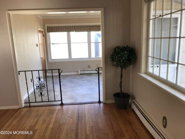 empty room featuring baseboard heating and dark wood-type flooring