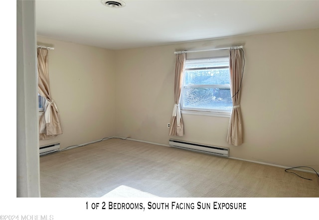 spare room with baseboard heating and light colored carpet