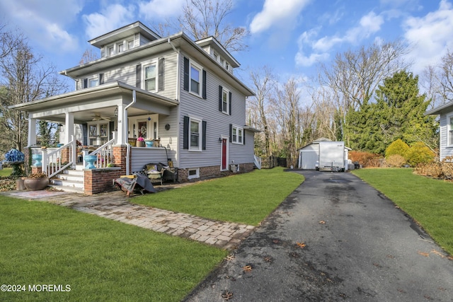 view of front of house with a garage, covered porch, an outbuilding, and a front yard