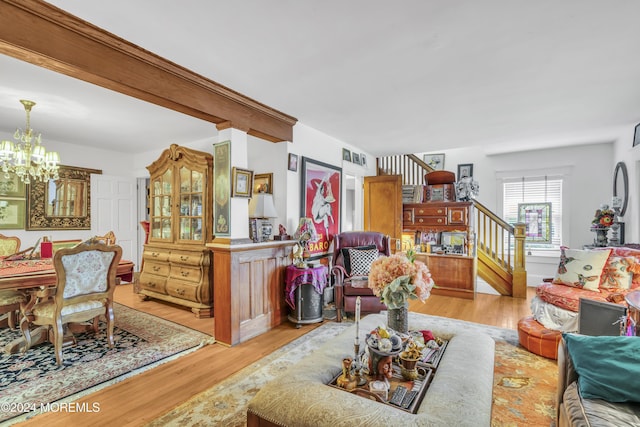 living room featuring beamed ceiling, light hardwood / wood-style floors, and an inviting chandelier