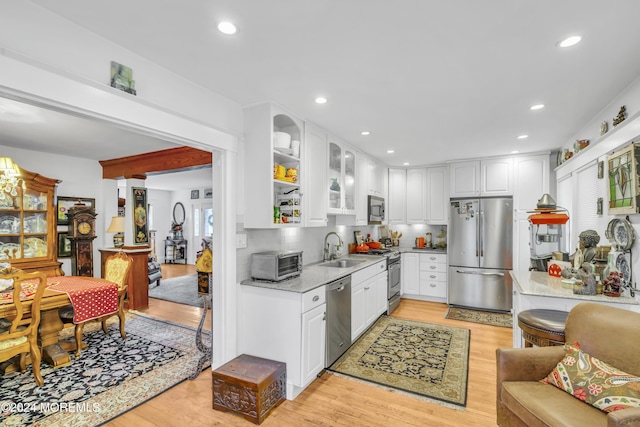 kitchen featuring sink, light hardwood / wood-style flooring, appliances with stainless steel finishes, light stone counters, and white cabinetry