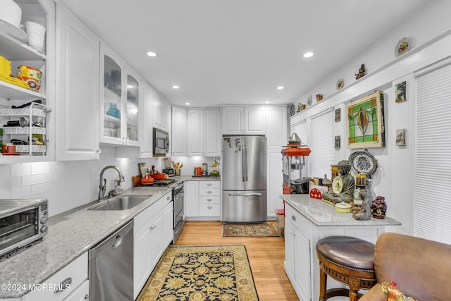 kitchen with light stone countertops, appliances with stainless steel finishes, light hardwood / wood-style flooring, and white cabinetry