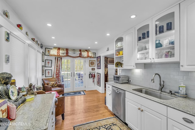 kitchen with white cabinetry, sink, stainless steel dishwasher, and light hardwood / wood-style flooring