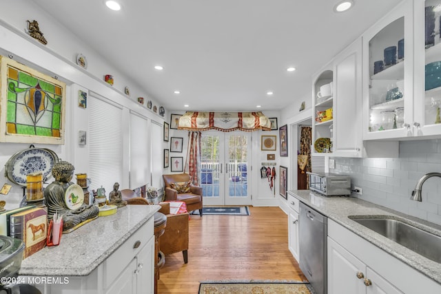 kitchen featuring dishwasher, light wood-type flooring, white cabinetry, and light stone countertops