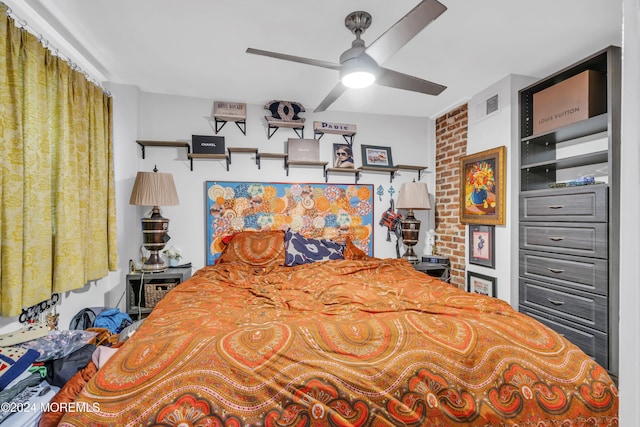 bedroom featuring ceiling fan and brick wall