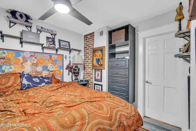 bedroom featuring wood-type flooring, ceiling fan, and brick wall