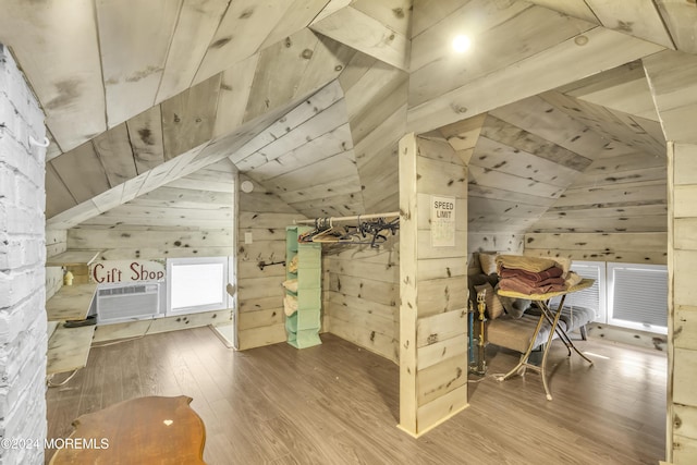 bedroom with wood ceiling, a wall unit AC, wooden walls, wood-type flooring, and lofted ceiling